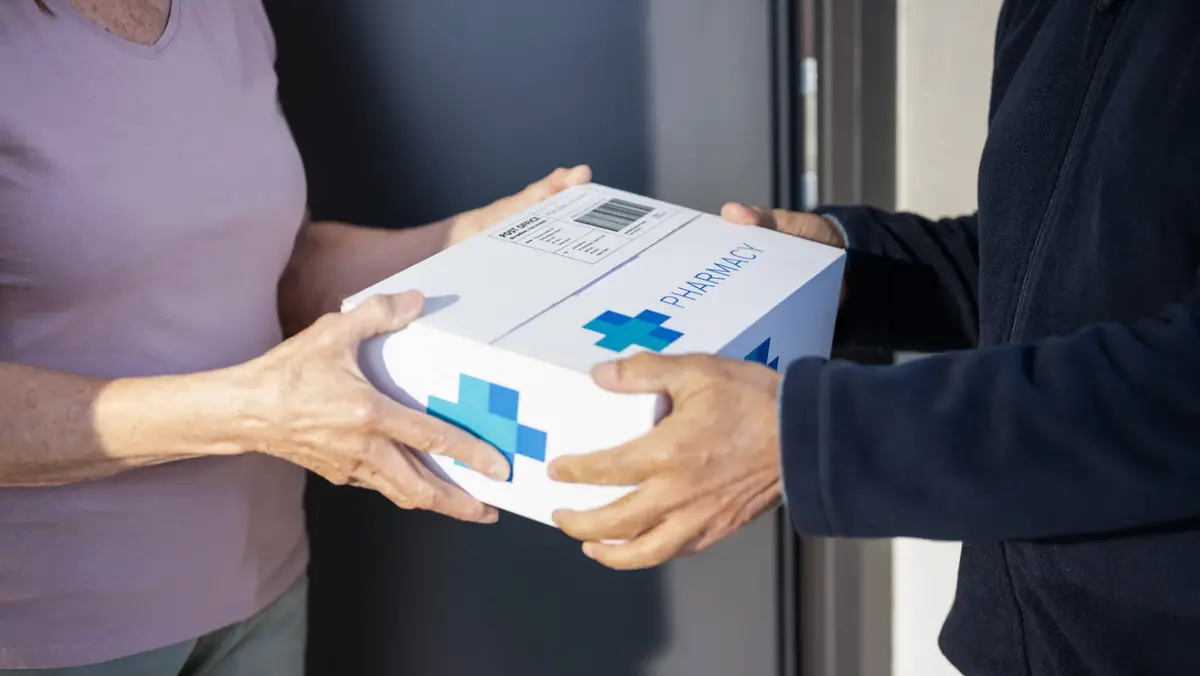 A pharmacy delivery box being handed to a patient at their door