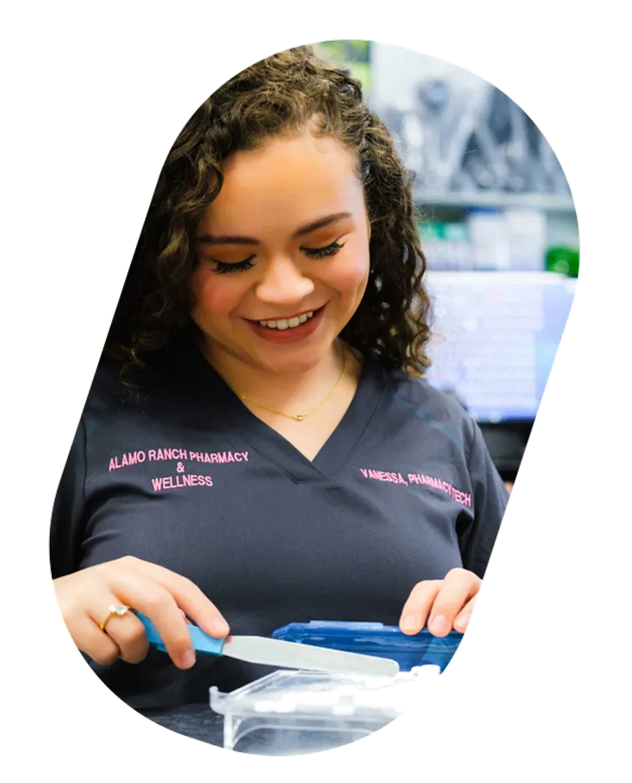 A smiling Alamo Ranch Pharmacy & Wellness pharmacy technician preparing medication